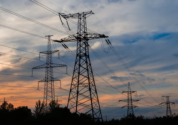 Elektrik direkleri ve gün batımında alacakaranlıkta çizgiler. — Stok fotoğraf