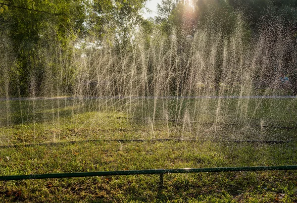 Gräsmatta sprinkler sprutar vatten över grönt gräs. Bevattningssystem — Stockfoto