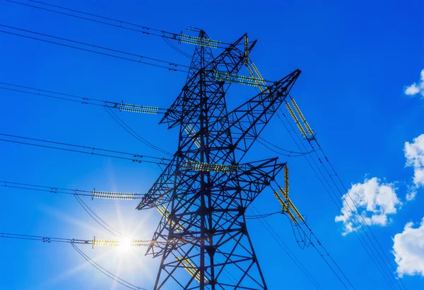 Power line silhouette against the blue sky with rays of sunlight. Stock Image