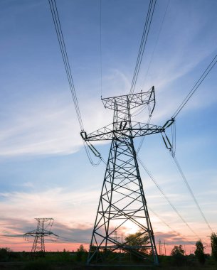 Gün batımında ya da gün doğumunda yüksek voltajlı elektrik hatları. Yüksek voltajlı elektrik iletim kulesi.