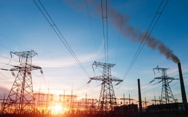 Gün batımında yüksek voltajlı elektrik hatları. Termik santral. Yüksek voltajlı trafo alt istasyonu.