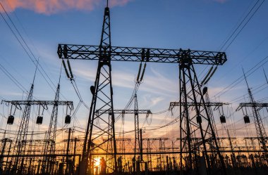 Gün batımında ya da gün doğumunda yüksek voltajlı elektrik hatları. Yüksek voltajlı elektrik iletim kulesi.