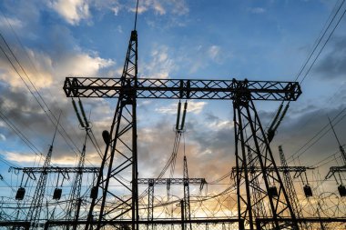 Gün batımında yüksek voltajlı elektrik hatları. Termik santral. Yüksek voltajlı trafo alt istasyonu.