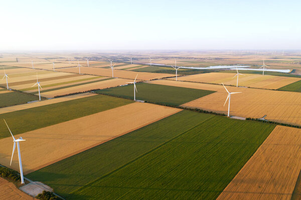 Sunset over the windmills. Wind turbines over fields of wheat and sunflowers.