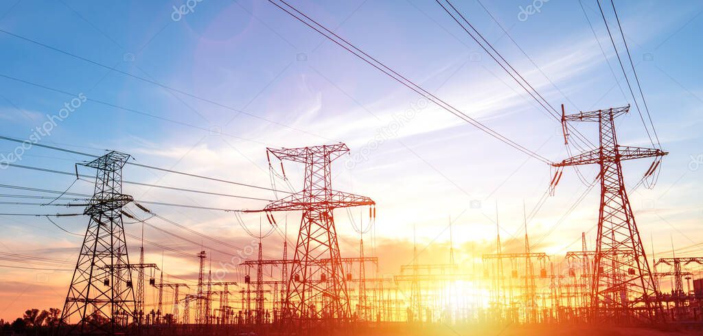 High-voltage power lines at sunset or sunrise. High voltage electric transmission tower.