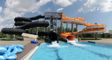 Su parkı, havuzlu parlak renkli slaytlar. Güzel, mavi gökyüzü bulutlu bir yaz gününde insanların olmadığı bir su parkı..