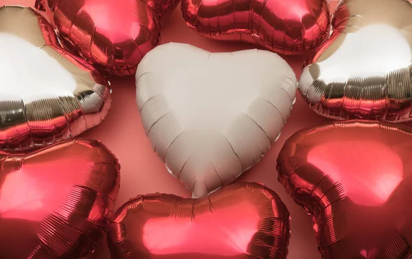 Heart-shaped balloon as a symbol of Valentine\'s Day. Background of foil balloons in the shape of a heart in shades of red.