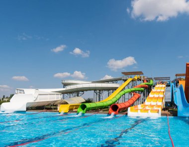 Su parkı, havuzlu parlak renkli slaytlar. Güzel, mavi gökyüzü bulutlu bir yaz gününde insanların olmadığı bir su parkı..