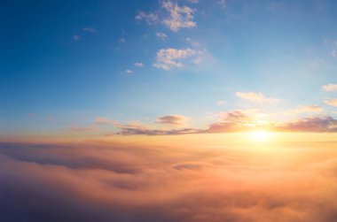 Kırmızı ve turuncu gölgeli bulutların üzerinde doymuş güzel bir gündoğumu olan bir uçaktan panoramik manzara.