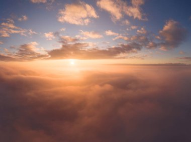 Bulutların üzerinde doymuş güzel bir gündoğumu olan bir uçaktan manzara.