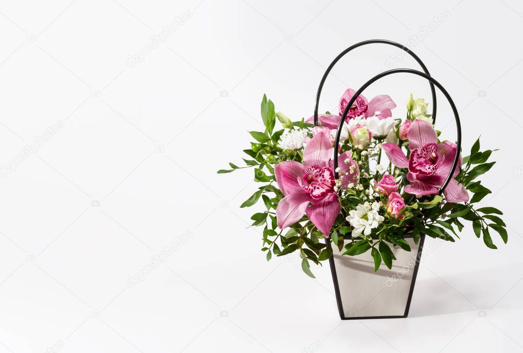 delicate orchids in a gift box or basket on a light background. space for text. bouquet of orchids, roses and chrysanthemums. festive postcard.