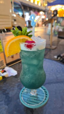 Taze meyve çeşitleriyle süslenmiş bu canlı mavi tropikal kokteyl şık bir bardakta Bangkok Tayland 'da servis edilir.