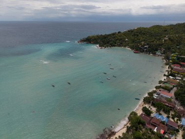 Tekneleri ve bungalovları olan sahil şeridi, rıhtımı ve palmiye gölgeleri olan canlı sahil topluluğu Koh Tao Tayland
