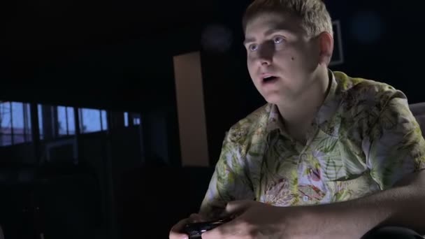 Un jeune homme avec une console de jeu dans un café chambre sombre avec passion jeu vidéo passionné — Video