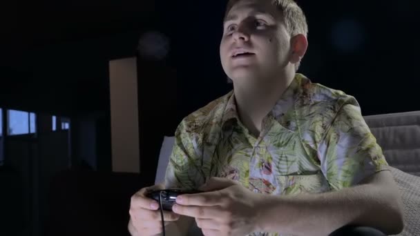 Ένας νεαρός άνδρας με μια κονσόλα παιχνιδιών σε ένα σκοτεινό δωμάτιο Cafe με πάθος έντονο υπολογιστή παιχνίδι — Αρχείο Βίντεο