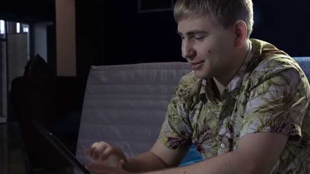 Jovem trabalhando em um laptop em um café à noite, imprime o texto se comunica no Skype — Vídeo de Stock