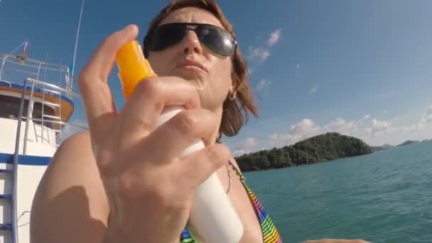 Femme se tient sur le nez Yachts en maillot de bain avec écran solaire à la main — Video
