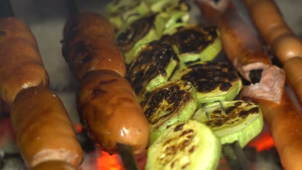 Kiełbasy i cukinia z grilla na szaszłyki na węglach tlący się ogień — Wideo stockowe