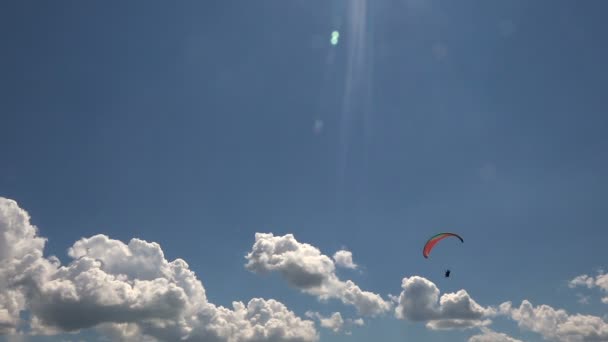 Parapente volant sur fond de beaux nuages et de soleil éblouissant. Été, Journée ensoleillée . — Video