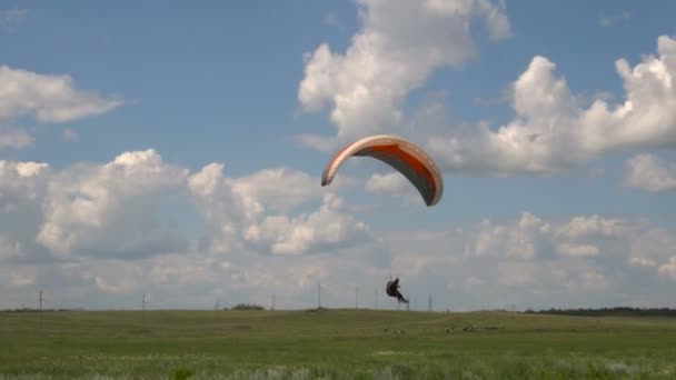 Медленное движение. Полет на параплане, посадка на зеленое травяное поле — стоковое видео