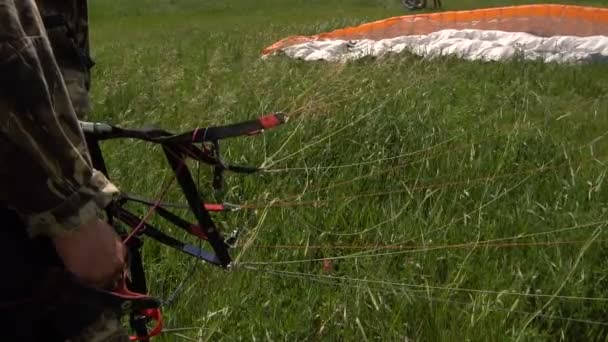 Paragliding v pomalém pohybu. Ruce sportovec před začátkem padákový kluzák v terénu. — Stock video