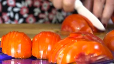 Büyük kadınların elleri üzerinde kurulu olgun kırmızı domates Semicircles kesilmiş