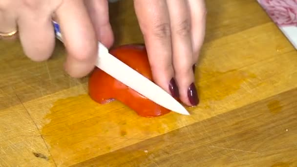 Las manos grandes de las mujeres fueron cortadas en un tablero semicírculos maduros de los tomates rojos — Vídeo de stock