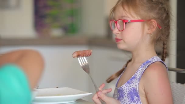 Girl eats sausage on a fork — Stock Video