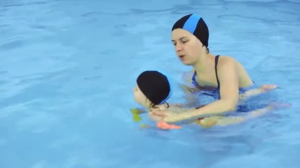 Madre enseña a niña a nadar en una piscina — Vídeos de Stock