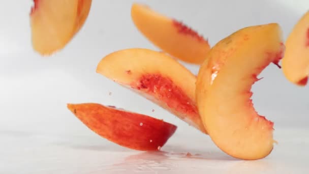 Шматочки персика падають на вологу поверхню — стокове відео