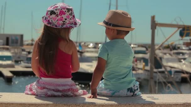 Malý chlapec a dívka sedící na molu Yacht Club — Stock video