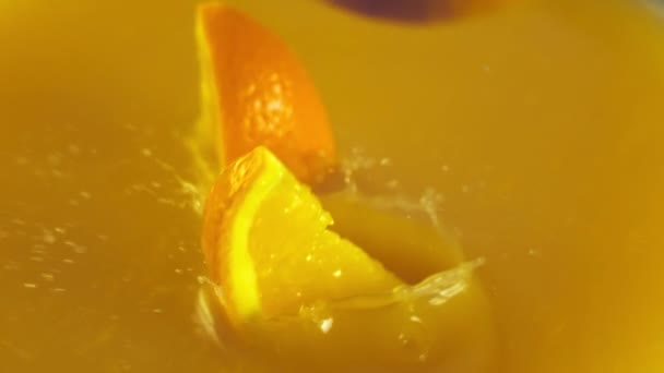 Rodajas de naranja cayendo en el jugo de naranja — Vídeos de Stock