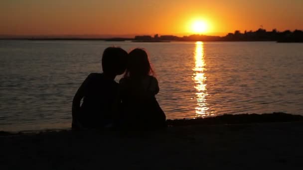 男の子と女の子は、夕日を見ています。 — ストック動画