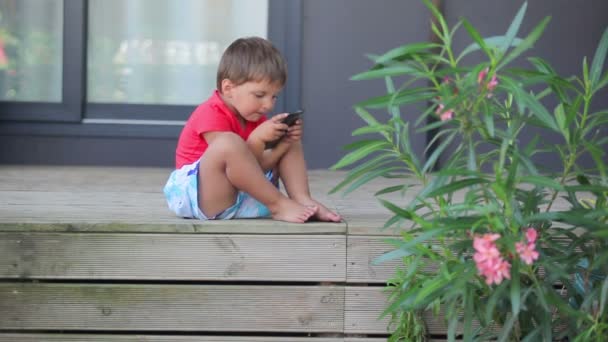 Pojke spelar på en mobiltelefon — Stockvideo