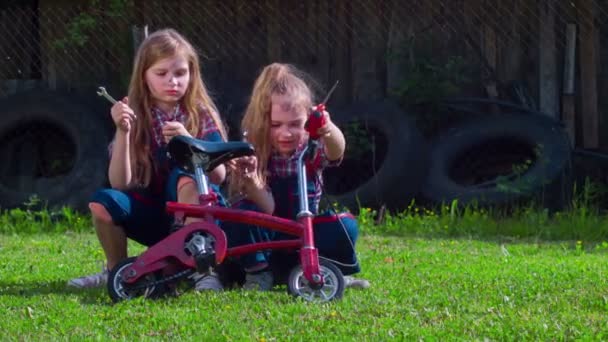 Dos chicas en una bicicleta reparación solar verde glade — Vídeo de stock