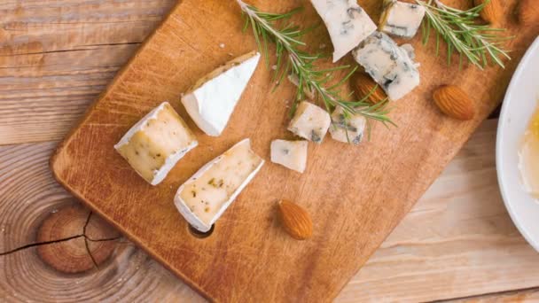 View from above on a wooden table with slices of cheese, nuts, rosemary, honey comb — Stock Video