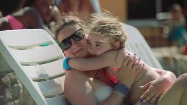 Anne ve kızı sahilde şezlong üzerinde yalan