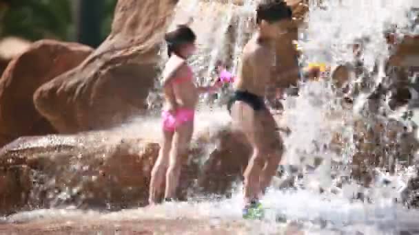 Mädchen spielt mit Wasserpistole in der Nähe eines Wasserfalls — Stockvideo