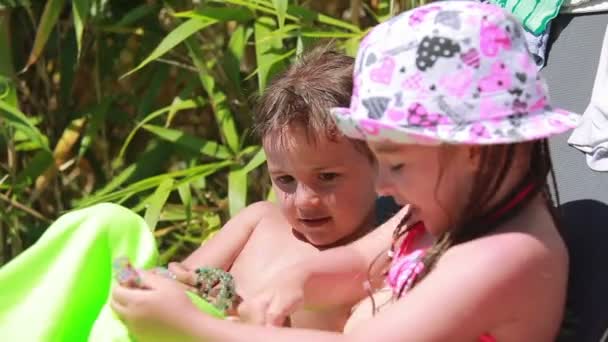 Niños jugando tumbados en una tumbona en la playa — Vídeo de stock