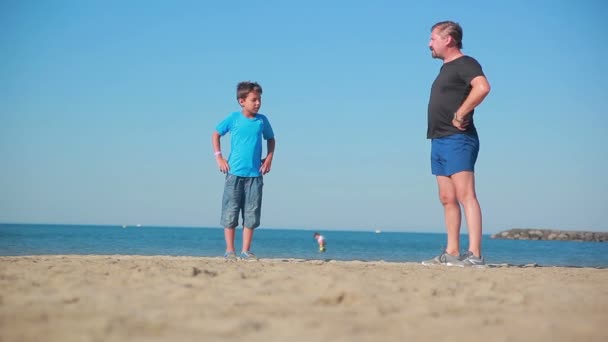 Niño y hombre haciendo ejercicios deportivos en la playa — Vídeos de Stock