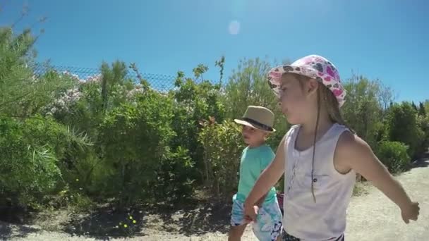 Klein meisje en jongen hand in hand, gaan over op de weg — Stockvideo