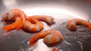 Bir yığın lezzetli kabuklu karides tavadaki ısıtılmış zeytinyağının üzerine düşüyor.