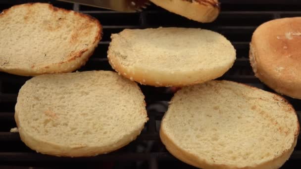 Kvinnlig hand är roterande hamburgare bullar med kök tång — Stockvideo