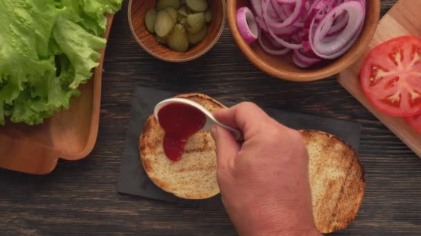 Bereiding van de zelfgemaakte gegrilde hamburger met vleessnijder, tomaten, sla — Stockvideo