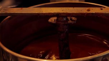 Çikolata atölyesindeki şekerleme karıştırıcısına koyu çikolata karıştırılır.