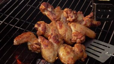 Lezzetli tavuk kanatları ızgara ızgarasında mutfak maşasıyla takla atıyor.