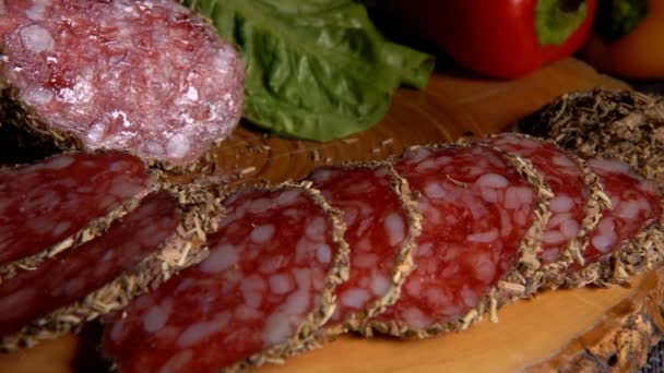 Panorama of delicious dry sausage in herbs taken from a wooden board with a fork — Stock Video