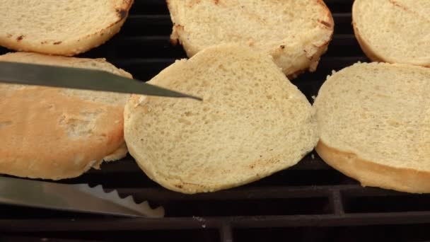 Les pinces de cuisine tournent des pains burger sur le gril — Video