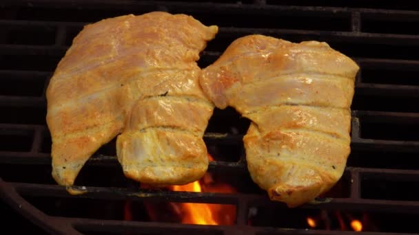 Primer plano del filete de pollo crudo freír en la rejilla de la parrilla en llamas — Vídeo de stock