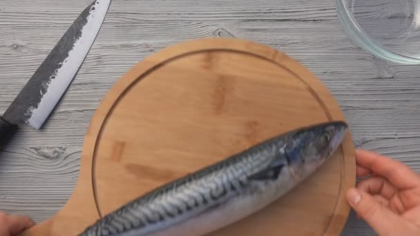 Widok z góry męskie ręce wprowadzenie makreli ryby na okrągłą deskę drewnianą — Wideo stockowe